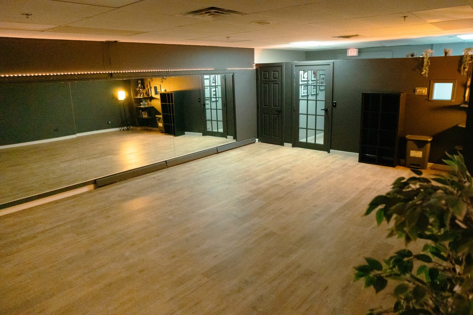 The Lab: an empty studio with a mirror along one wall, a wood floor and a dark back wall lit by a warm strip light.